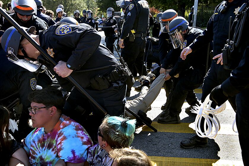 In this photo taken Wednesday, Feb. 12, 2020, University of California police drag protesters from High Street and arrest them in Santa Cruz, Calif. Officials say at least 17 people were arrested during the third day of a wildcat strike by University of California, Santa Cruz graduate students demanding higher pay. The Santa Cruz Sentinel reports that police arrested the group Wednesday after demonstrators blocking an intersection near campus ignored multiple orders to disperse. (Dan Coyro/Santa Cruz Sentinel via AP)