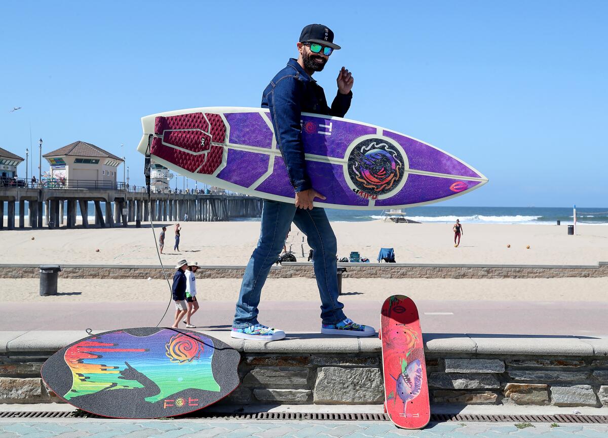 Founder TiMo Tidwell stands with his board with the TIOIT surf grip on the deck at Pier Plaza in Huntington Beach.