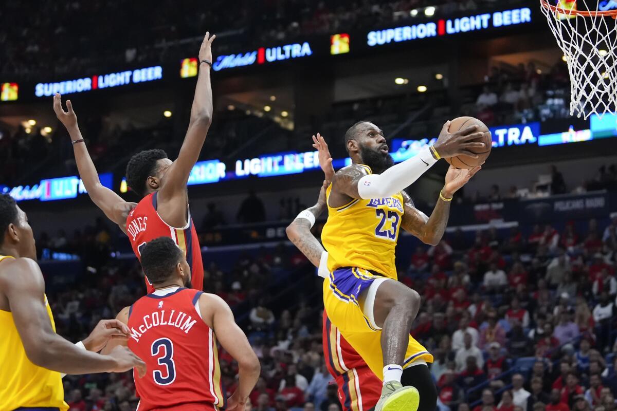 Lakers forward LeBron James gets past Pelicans defenders for a layup Tuesday night.