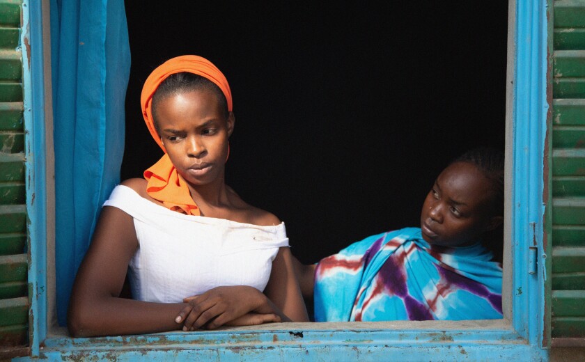 Two African women look out an open window.