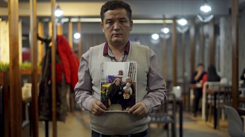 Tursynbek Kuzhyrbek, a Chinese-born immigrant to Kazakhstan, holds a picture on Dec. 7 of his parents. Kuzhyrbek says his father, an elderly retiree, was forced to work at a factory in China's far western Xinjiang region for four months before being allowed to return home.