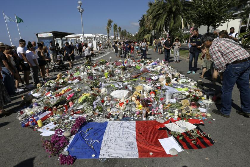 FILE - People look at flowers placed on the Promenade des Anglais at the scene of a truck attack Monday July 18, 2016 in Nice, southern France. A French court on Tuesday Dec.13, 2022 convicted eight people charged in connection with a truck attack more than six years ago by an Islamic State sympathizer that killed 86 people celebrating Bastille Day in the French Riviera city of Nice. (AP Photo/Claude Paris, File)