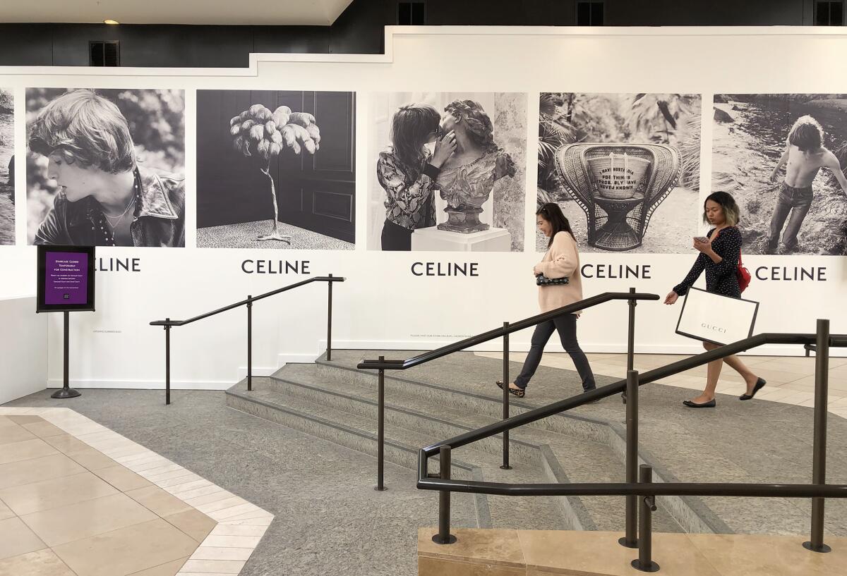 Shoppers stroll through a mostly empty South Coast Plaza in Costa Mesa on March 16, hours before the mall closed to the public for two weeks after a store employee tested positive for the coronavirus. A mall spokeswoman said Monday that it is staying closed until further notice.