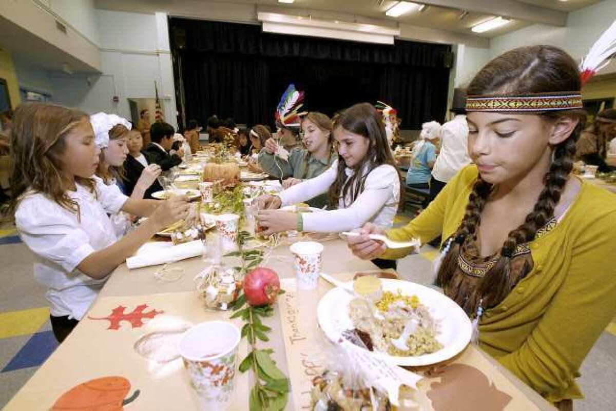 Claire Kevorkian, a 5th grader, enjoys a Thanksgiving meal during lunch at La Canada Elementary School in La Canada on Friday. The annual event has the 5th grade classes dress up in costumes and are served the meal by volunteer parents.