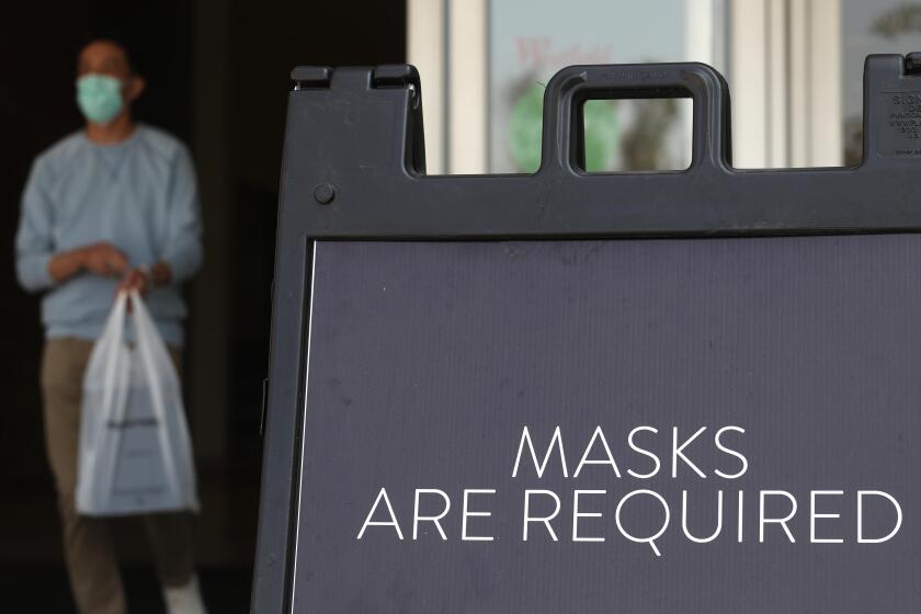 ARCADIA, CA - OCTOBER 07, 2020 - A sign tells customers to wear masks to prevent the spread of COVID-19 as shoppers return to indoor shopping at the Westfield Santa Anita shopping mall in Arcadia on October 7, 2020. This is the first day customers were allowed to return to indoor shopping after Los Angeles County eased restrictions and have reopened the malls and the individual stores. Such stores have been closed for weeks, but reopened Wednesday at 25% capacity. Westfield Santa Anita has placed Covid-related signage with one-way traffic, 6 feet distancing when waiting to get into individual stores, hand sanitizing stations and mask are required before entering the mall. (Genaro Molina / Los Angeles Times)