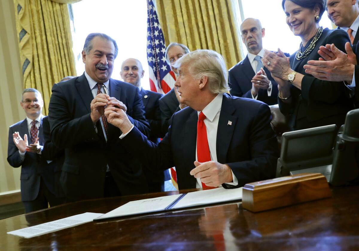 Andrew Liveris, left, and President Trump exchange a pen.