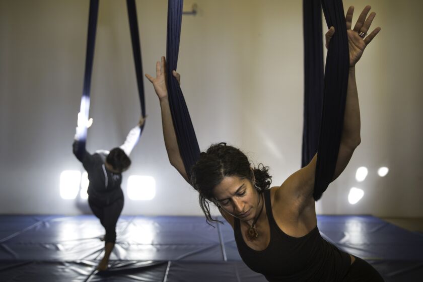 Instructor Veronica DeSoyza, right, leads a morning aerial yoga class at Kinship in Highland Park. Shelby Williams-Gonzalez, left, holds a pose.
