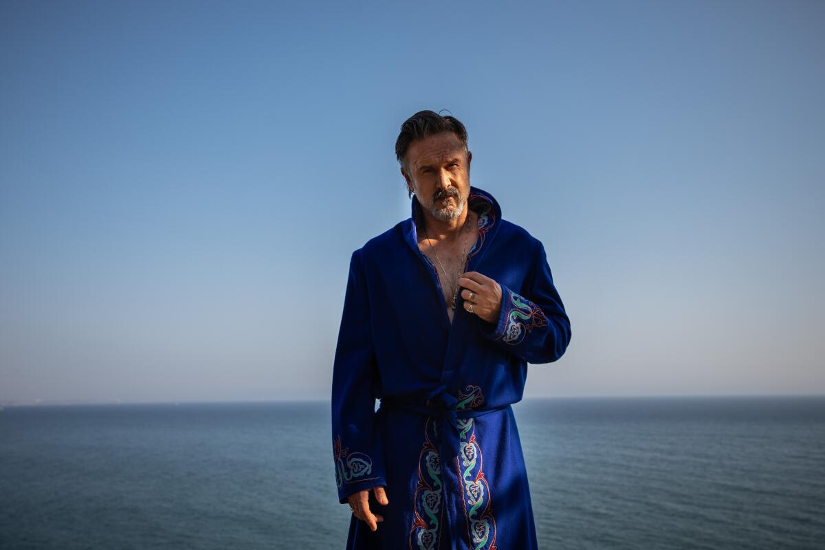 David Arquette is photographed in a vintage robe, channeling a wrestler and possibly Elvis, next to the Pacific Ocean.