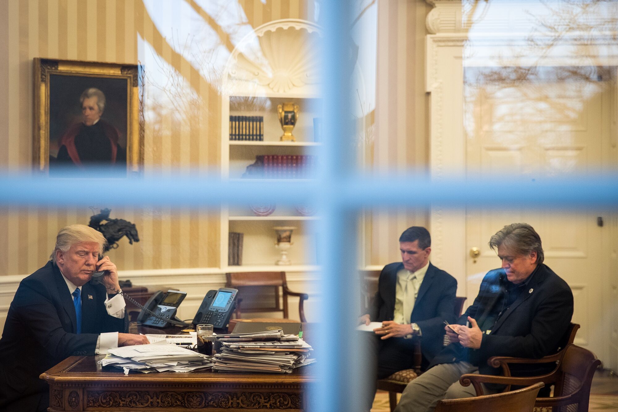 Donald Trump, Michael Flynn and Stephen Bannon are seen through a window.