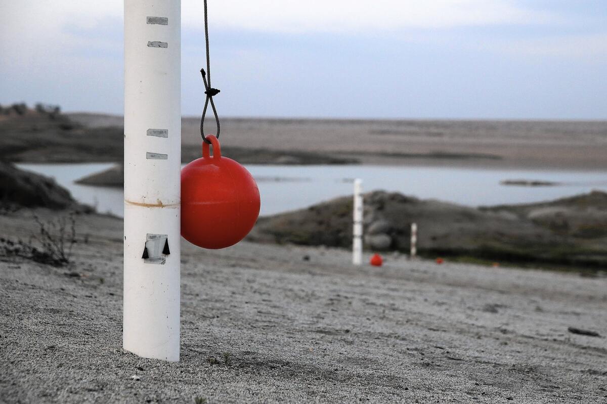 Water level markers stand on what used to be the bottom of Hensley Lake on April 23 in Raymond, Calif.
