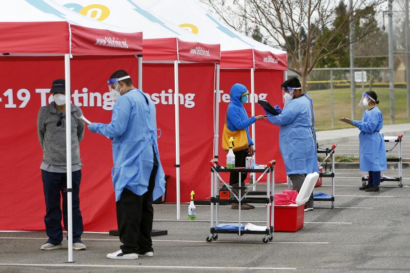 Clinic 360 medical assistants screen patients during a COVID-19 mobile testing site at Fountain Valley Sports Park on Tuesday morning.