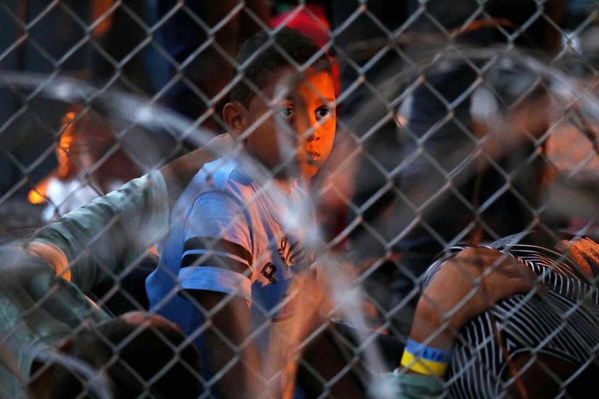 Migrants seeking asylum, including children, are held in a temporary transition area under the Paso Del Norte bridge in El Paso, Texas, in March.
