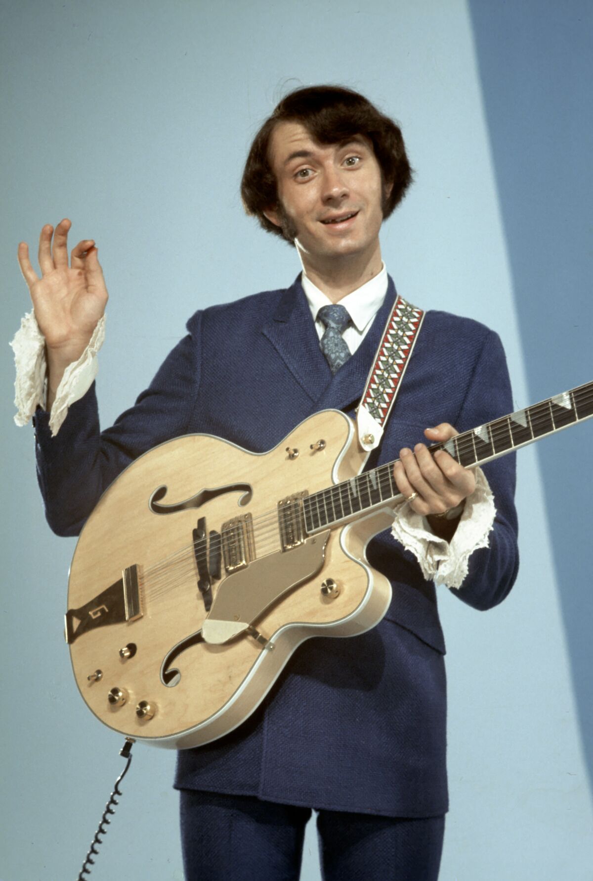 A man in a suit holding an electric guitar.