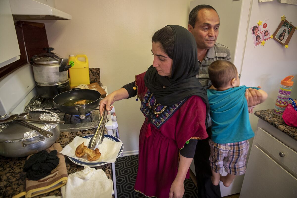 Naseema Kashefi, left, cooks vegetable samosas with her husband, Bashir, and son, Haroon, 2, at their Anaheim apartment. (Allen J. Schaben / Los Angeles Times)