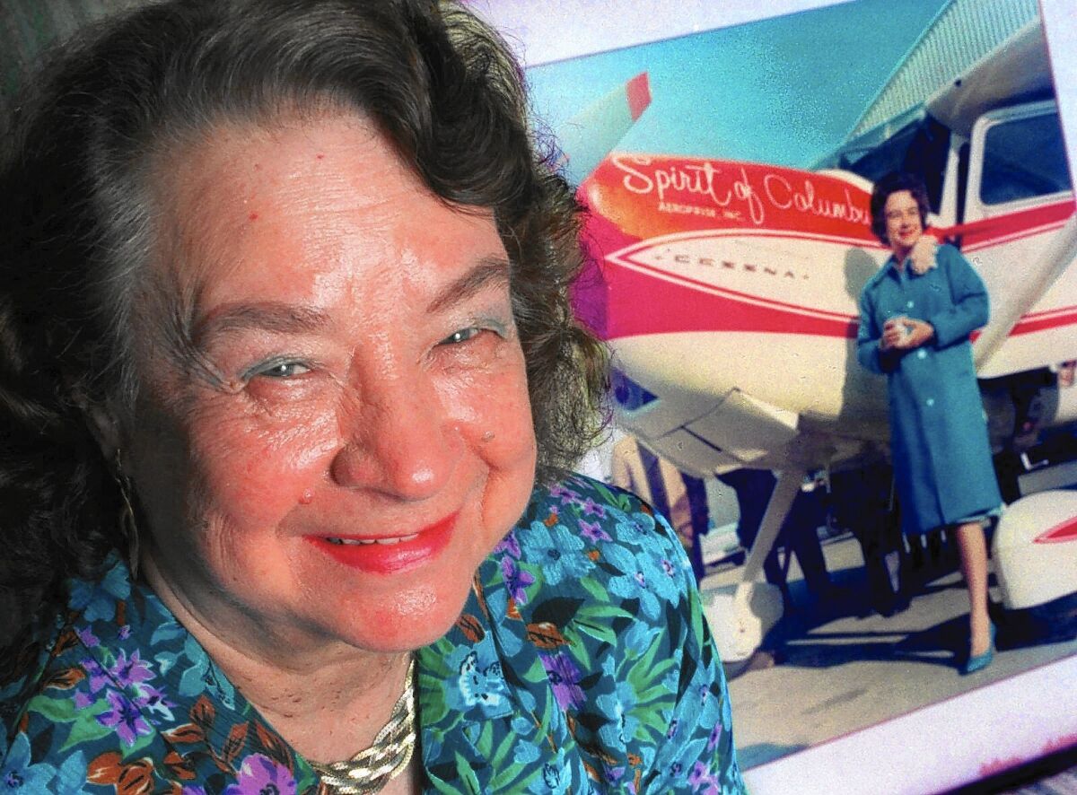 Geraldine "Jerrie" Mock poses next to a photograph of her that was taken minutes before she began her flight around the world in 1964.