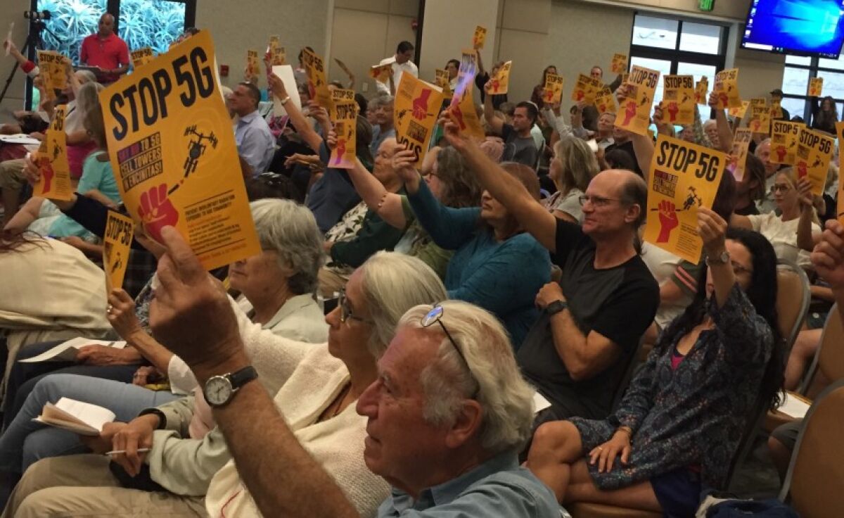 More than 150 people, many waving “Stop 5 G” posters, attend a city-sponsored workshop Monday on a new city ordinance that will allow 5G antennas to be installed along city rights-of-way.