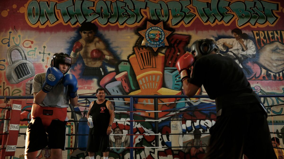 Boxing coach Paul Hernandez, 58, background, gives instructions to Isidro Mier, 14, left, and Angel Sanchez, 15, at the East Los Angeles Community Youth Center. Hernandez has been fighting to keep the gym from closing.