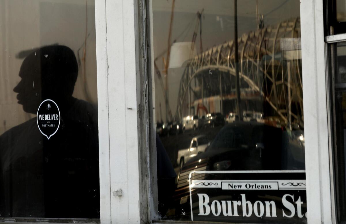 A customer's silhouette and the under-construction Inglewood stadium are reflected in the windows of Bourbon Street Fish on Jan. 30.