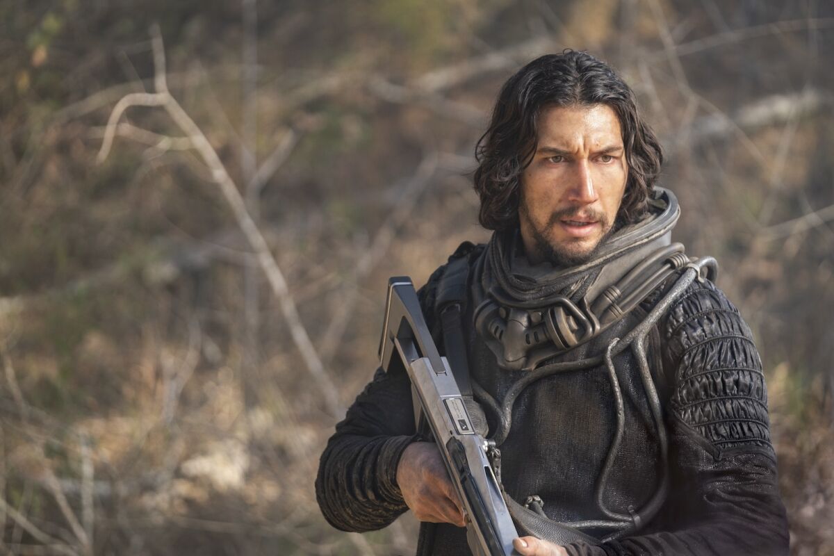 reviews movie windfall A man in a futuristic outfit holding a gun-like weapon and standing outdoors