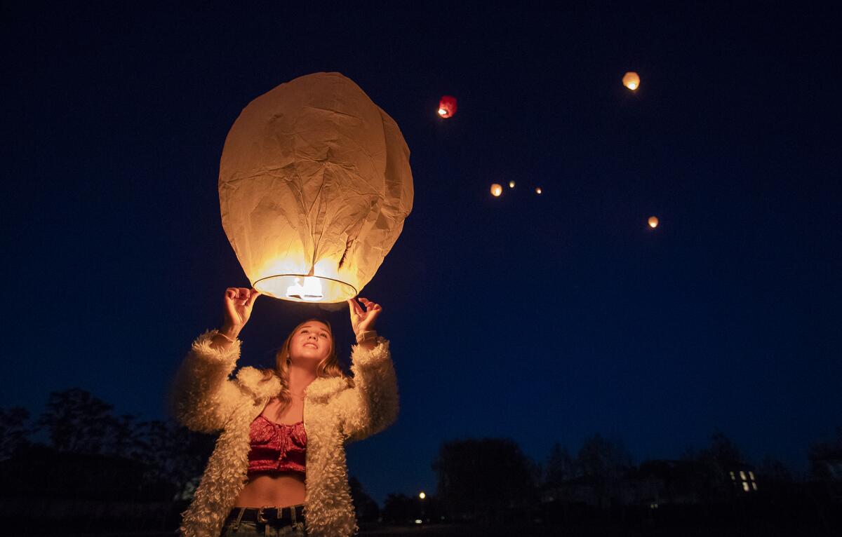 Kendall Heinrich prepares her sky lantern for launch during a surprise birthday celebration for her friend Madison Moore on Tuesday night in Huntington Beach.