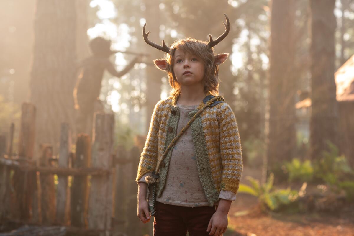 A young boy with deer antlers in a forest