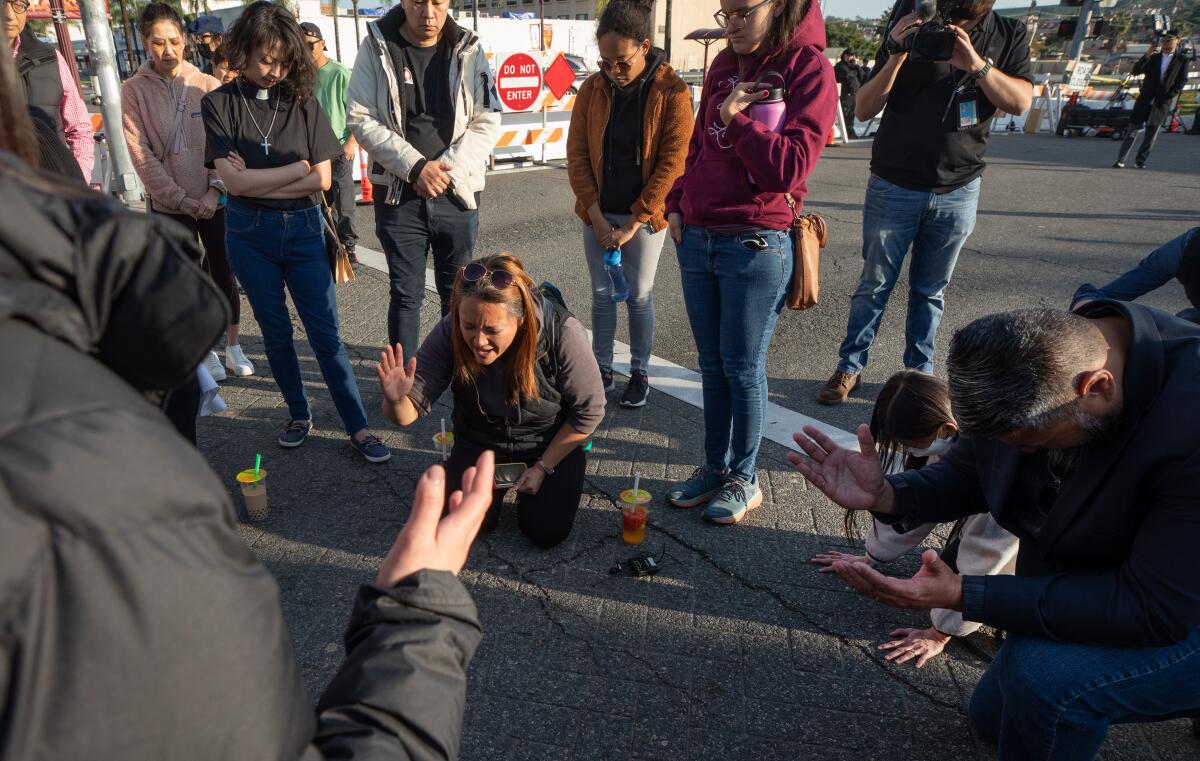 A prayer circle forms at Garvey and Garfield avenues in Monterey Park after a shooting at a ballroom dance studio.