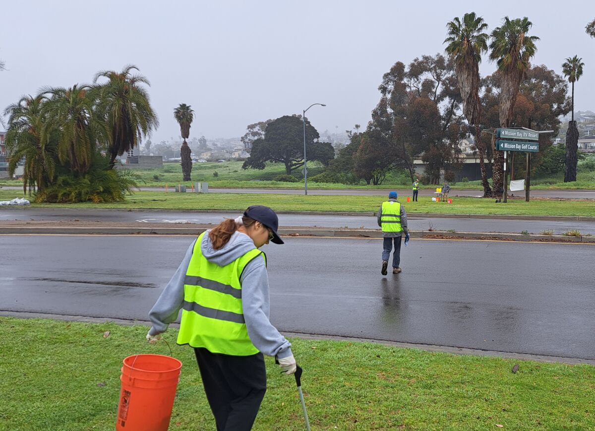 Armed with reach extenders and utility buckets, volunteers head across Mission Bay Drive to collect litter on March 11.