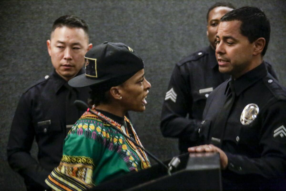 Police try to remove Jasmine Richards at a lectern after she exceeded the time limit at a Los Angeles Police Commission meeting on May 17, 2016. Before the meeting, Black Lives Matter members and others held a news conference criticizing the city.