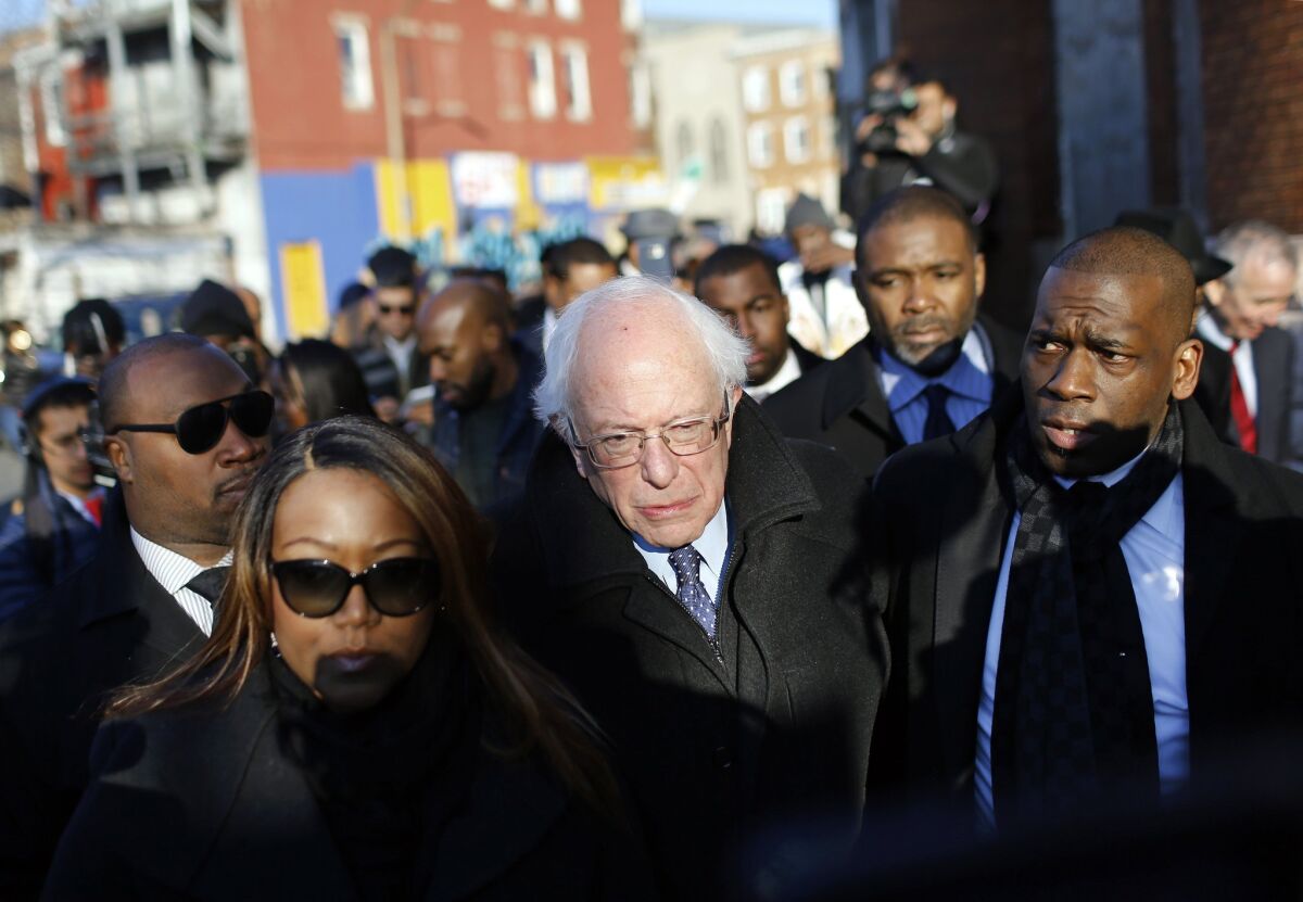 Democratic presidential candidate, Sen. Bernie Sanders, I-Vt., center, walks alongside the Rev. Jamal Bryant, right, during a walking tour of the Sandtown-Winchester neighborhood of Baltimore, Tuesday, Dec. 8, 2015. The Democratic candidate was touring the neighborhood of Freddie Gray, who died last spring of a spinal injury he suffered while in police custody, touching off riots. (AP Photo/Patrick Semansky)
