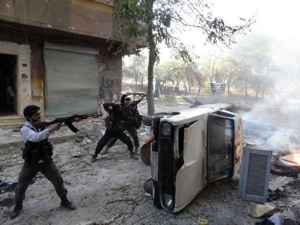 Rebel fighters open fire from behind a car during clashes in the the northern Syrian city of Aleppo on Wednesday.