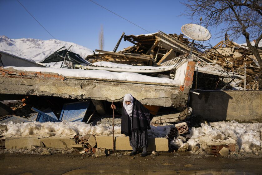 Zehra Kurukafa walks past a destroyed house in the village of Polat, Turkey, Sunday, Feb. 12, 2023. Five days after two powerful earthquakes hours apart caused scores of buildings to collapse, killing thousands of people and leaving millions homeless, rescuers were still pulling unlikely survivors from the ruins. (AP Photo/Francisco Seco)