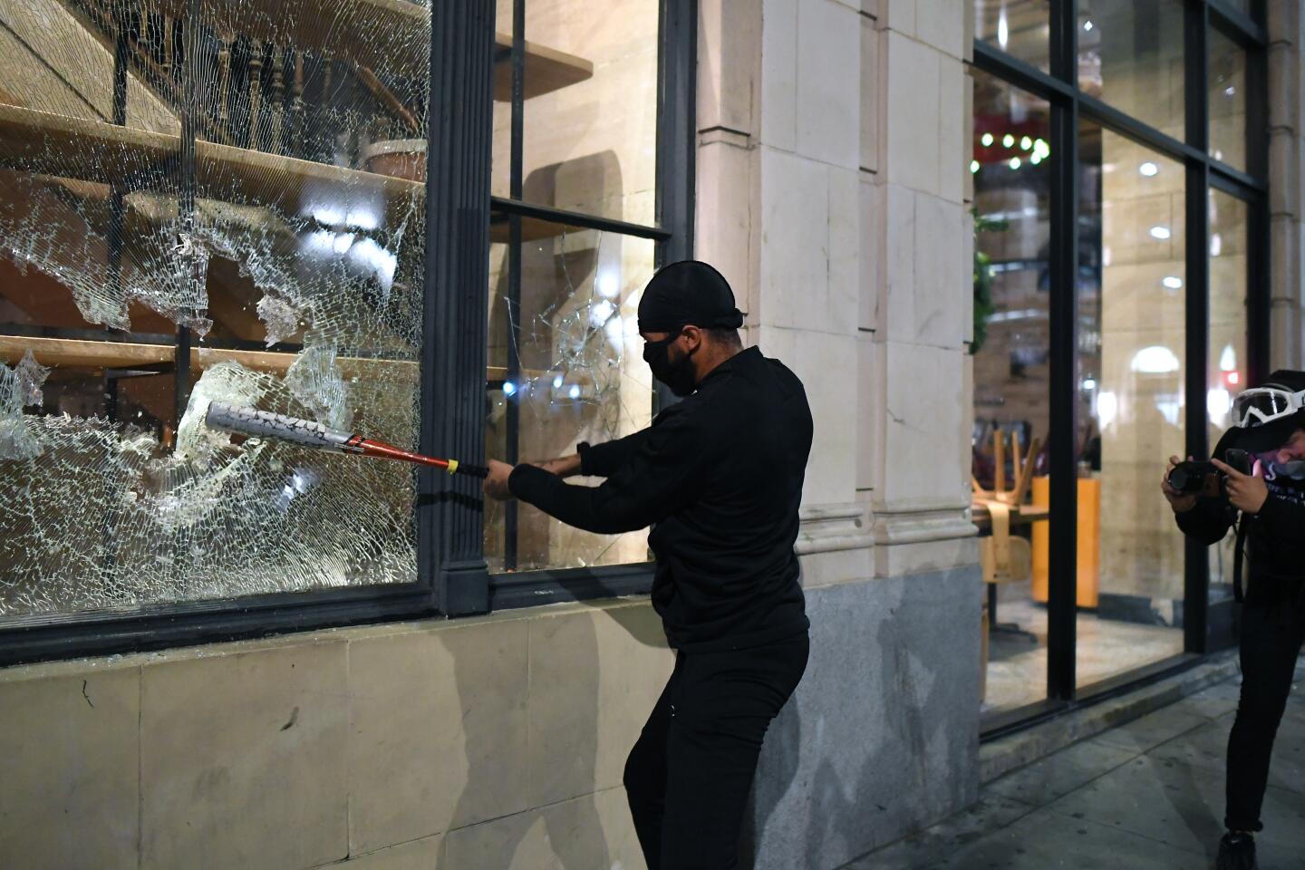 A man breaks a window with a bat in downtown Los Angeles