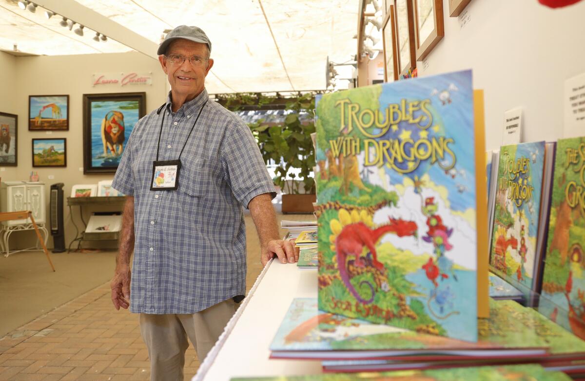 Longtime exhibitor Scott Sutton stands with his popular children's books about whimsical dragons at Laguna's Art-A-Fair.