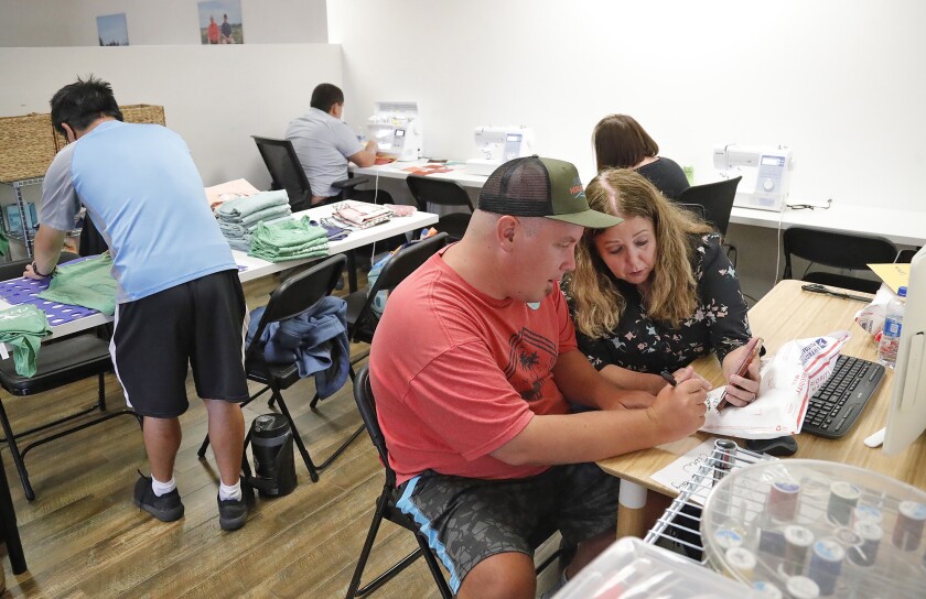 Founder Jennifer Tracy, helps Jonathan Guinn fill an online order for Surfers Healing at the Zuggy Etc. work space.