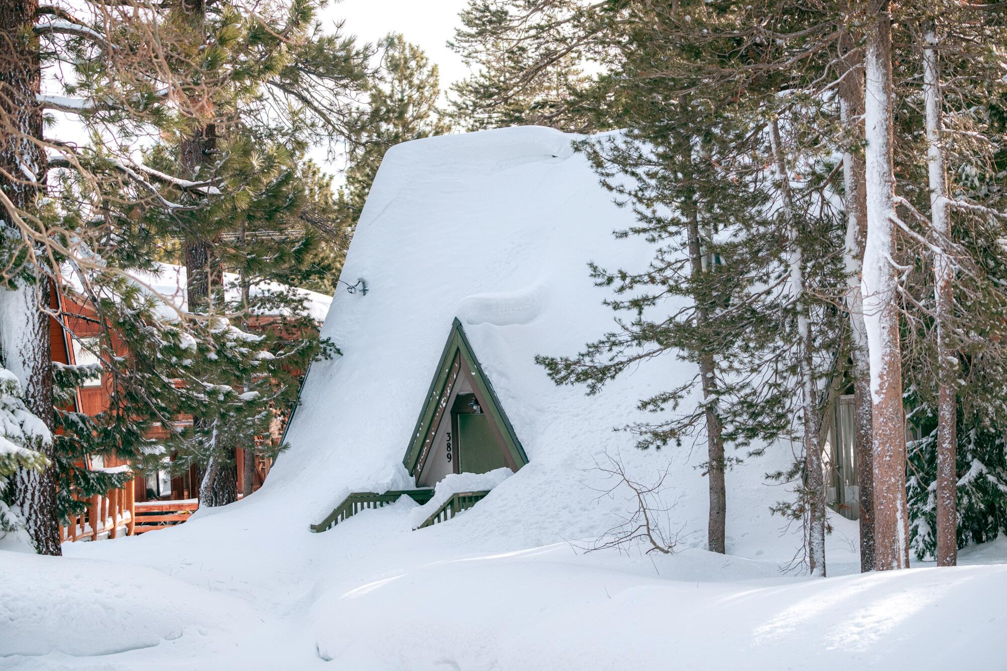 An A-frame cabin is buried under snow.