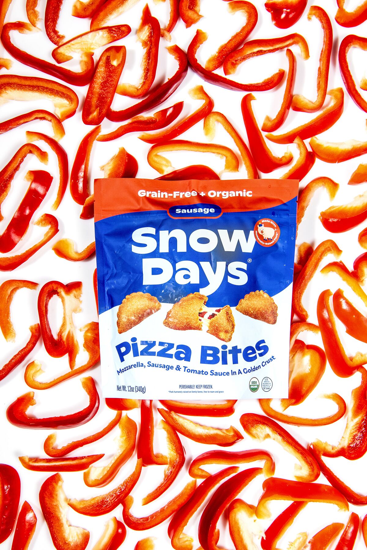 A package of Snow Days Pizza Bites on a background of red bell pepper slices.