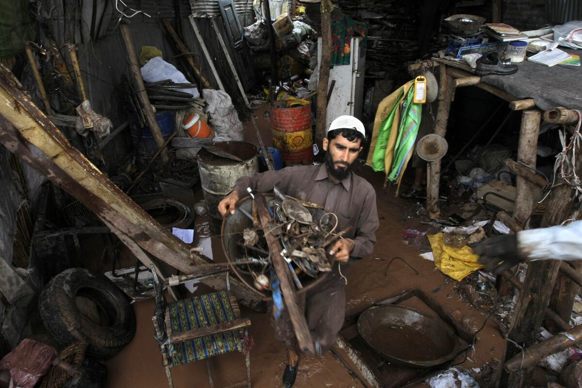 A man salvages his belongings from his flooded house on the outskirts of Peshawar. (Mohammad Sajjad / Associated Press)