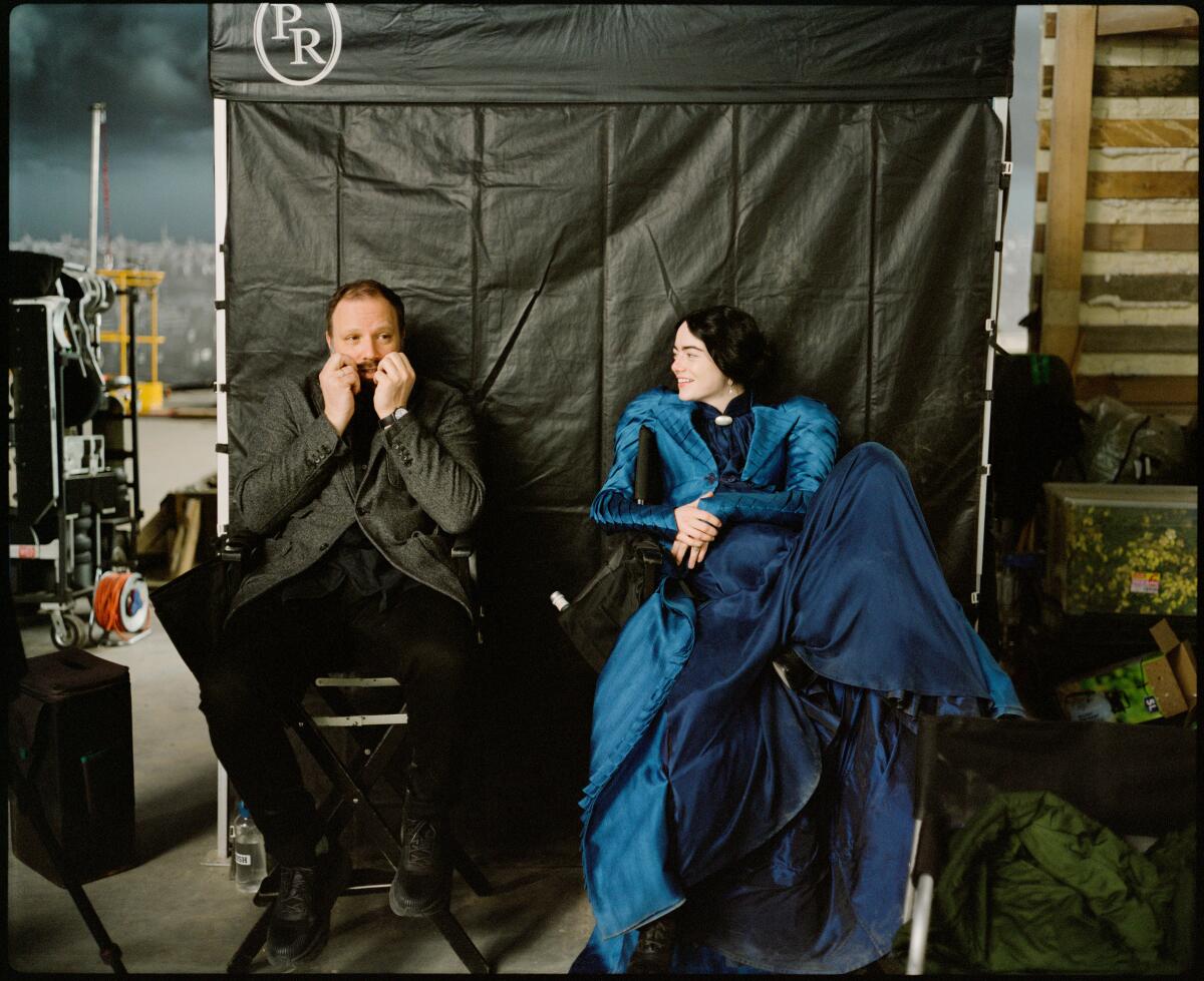 A man and a woman in a blue dress make a joke on a movie set.