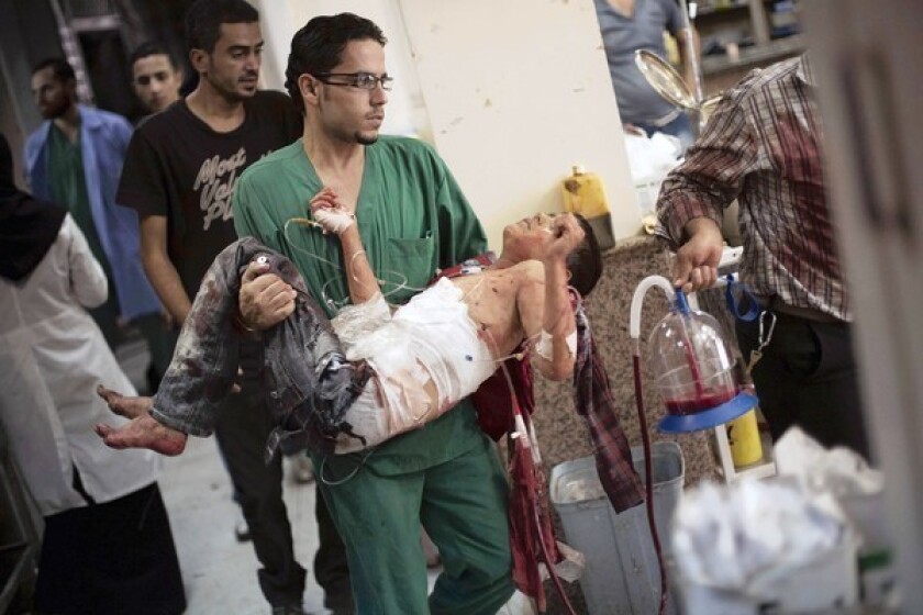 A doctor carries a badly wounded boy in a hospital in Aleppo, Syria.