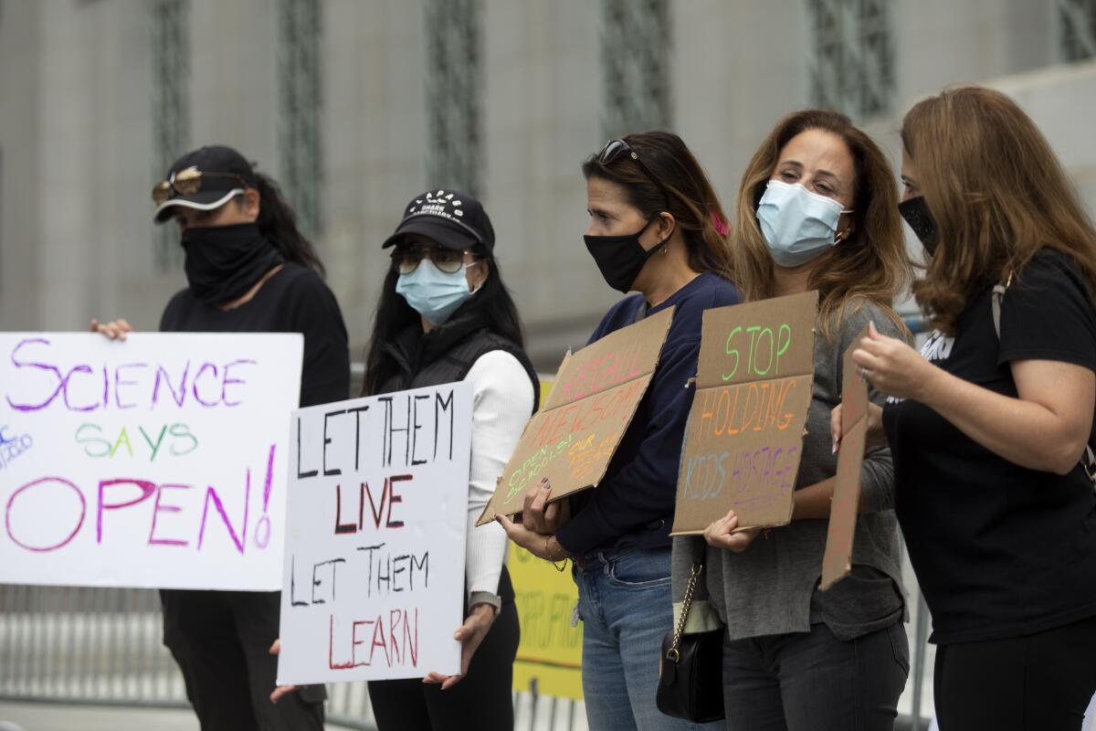 Five people holding signs and wearing masks