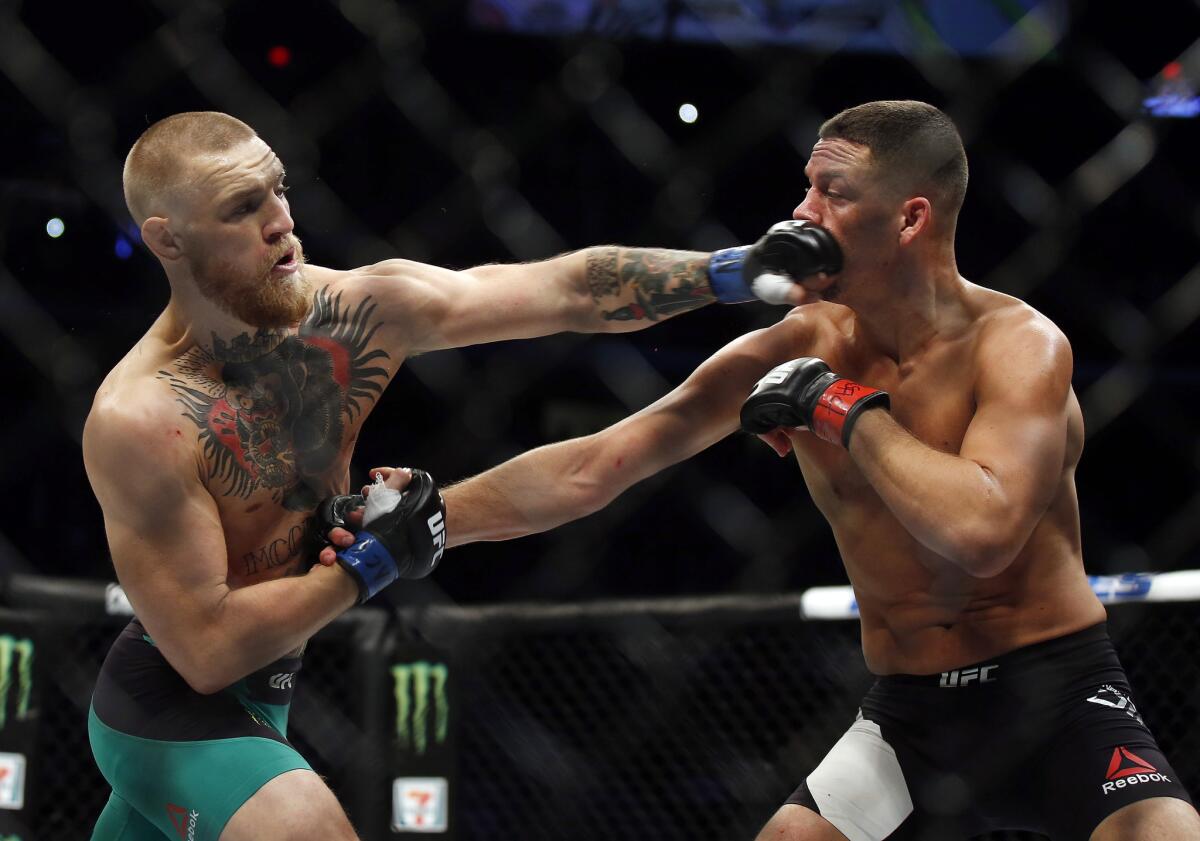 Conor McGregor, left, punches Nate Diaz during their welterweight bout Saturday at UFC 202, which McGregor won by majority decision.