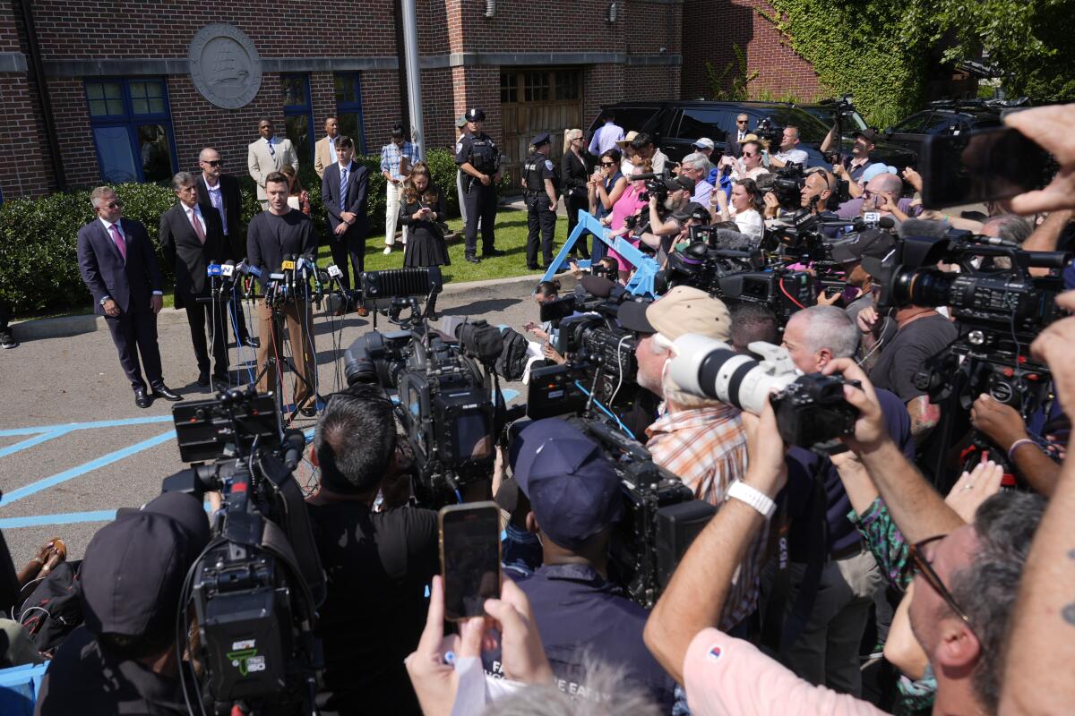 Justin Timberlake speaks to a large group of reporters and photographers outside a courthouse.