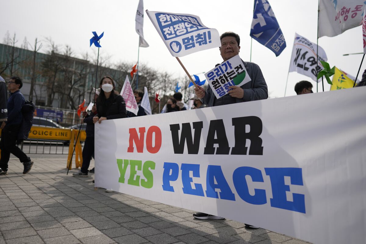 Protesters hold signs at a rally opposing the planned joint military exercises between the U.S. and South Korea in Seoul.