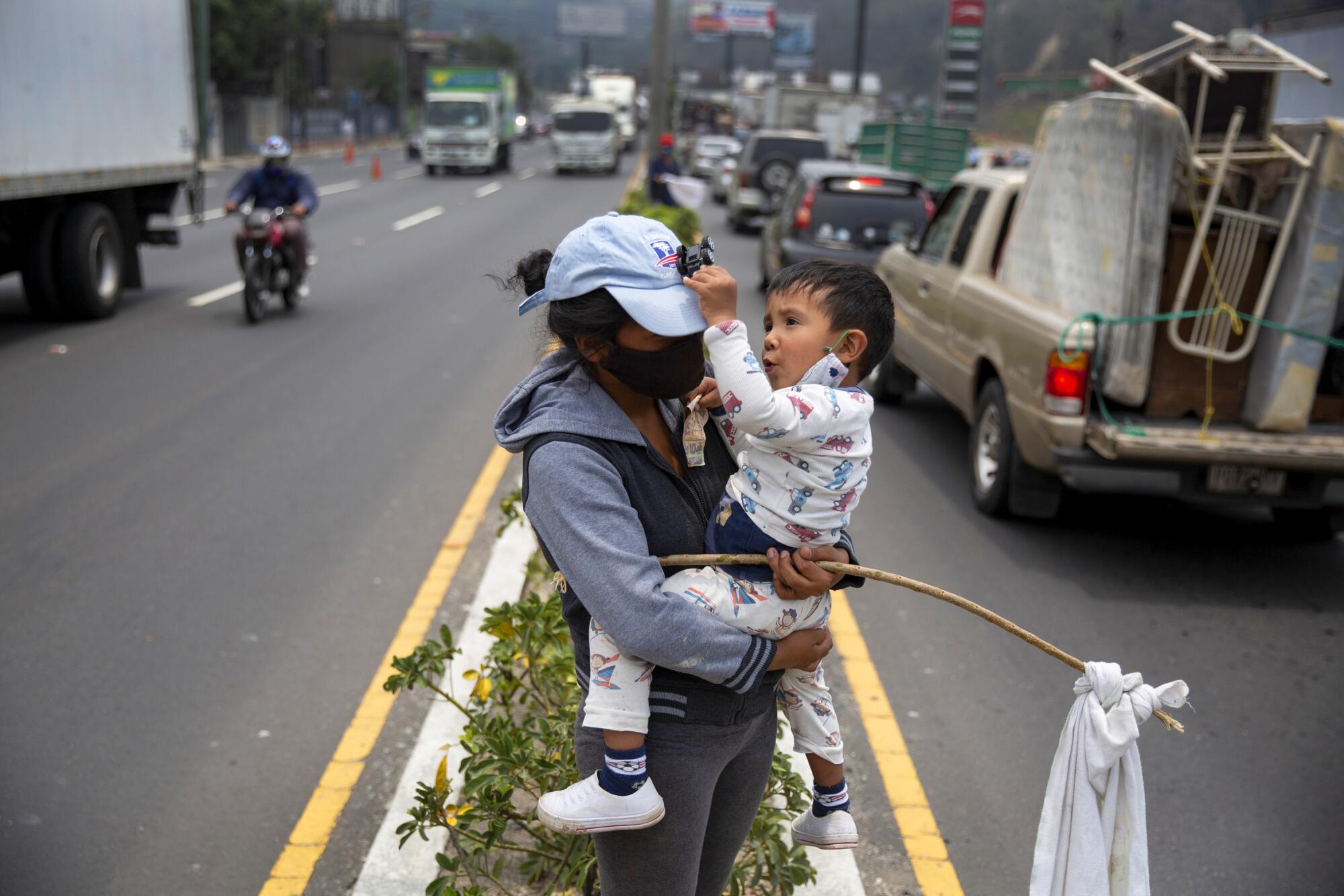 Una mujer con su hijo sostiene una bandera blanca como señal de que necesita asistencia alimenticia, el miércoles 6 de mayo, en Villa Nueva, Guatemala.