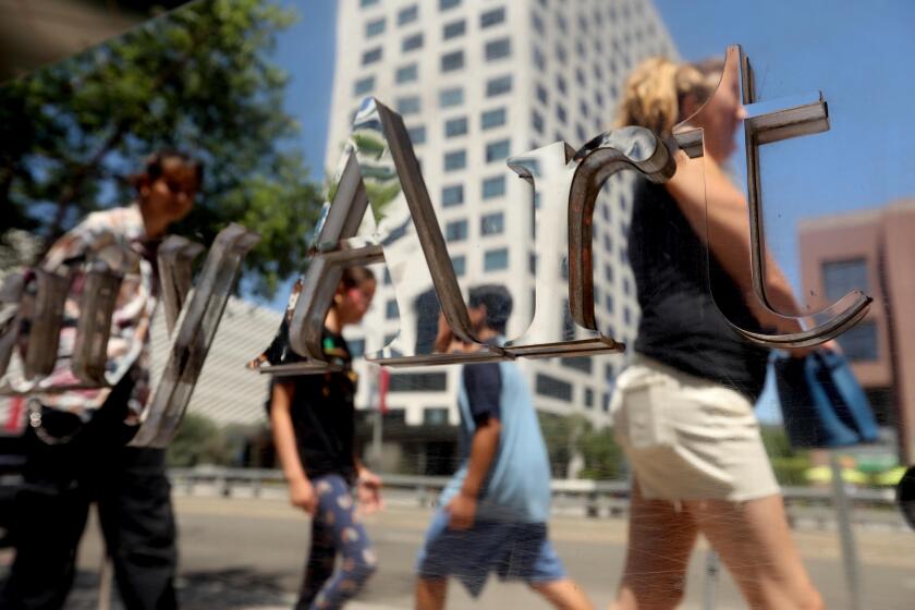 LOS ANGELES, CA - AUGUST 13, 2022 - - Pedestrians are reflected in a mirrored panel of the Museum of Contemporary Art, Los Angeles, (MOCA) on another hot afternoon in Downtown Los Angeles on August 13, 2022. (Genaro Molina / Los Angeles Times)