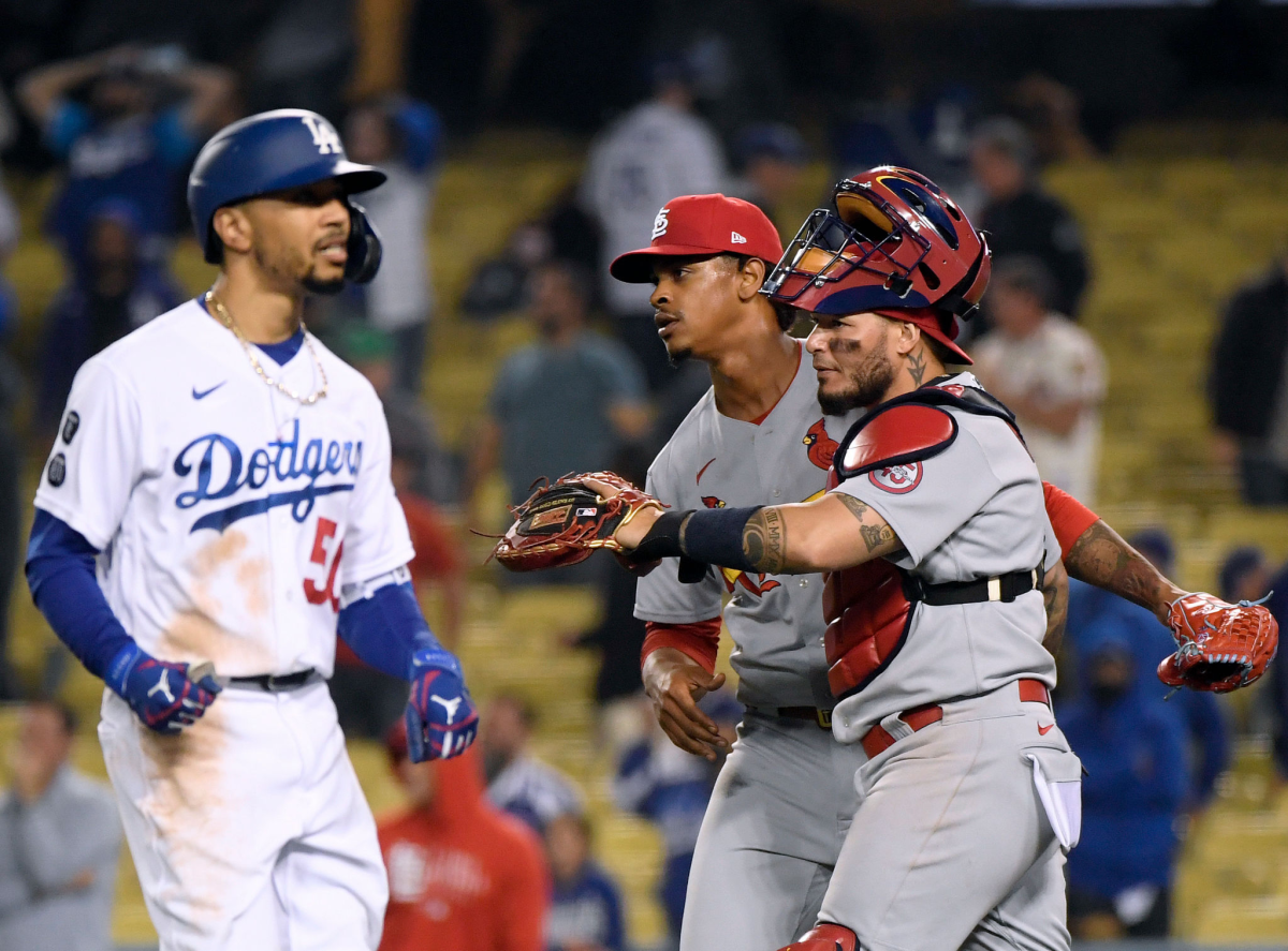 The Dodgers' Mookie Betts heads to the dugout as the Cardinals' Alex Reyes (29) and Yadier Molina (4) celebrate a  win.