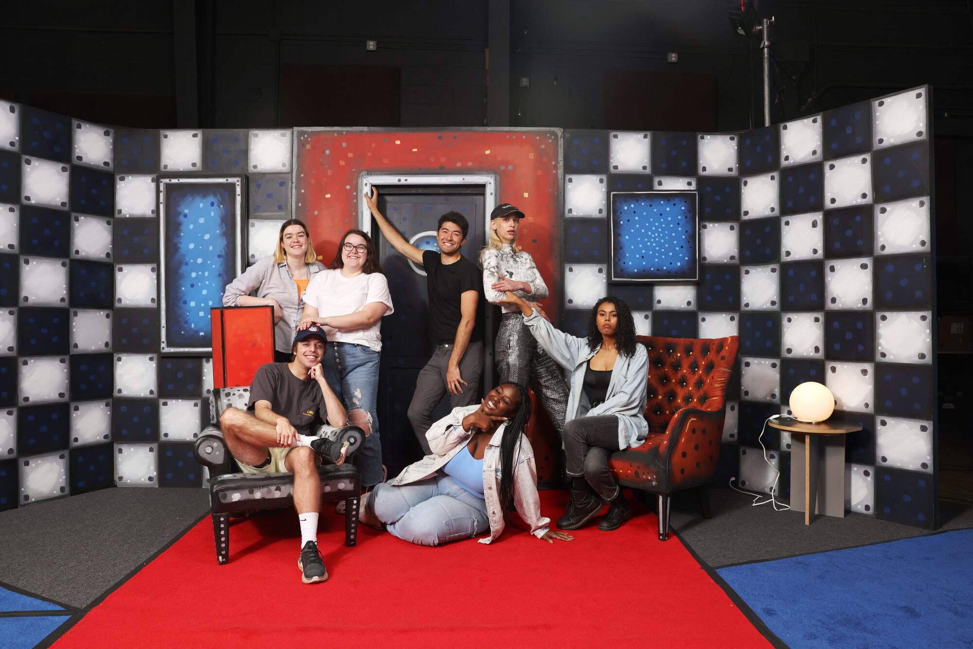 The cast of "Stapleview" on a set of checkboard walls and red and blue decor.