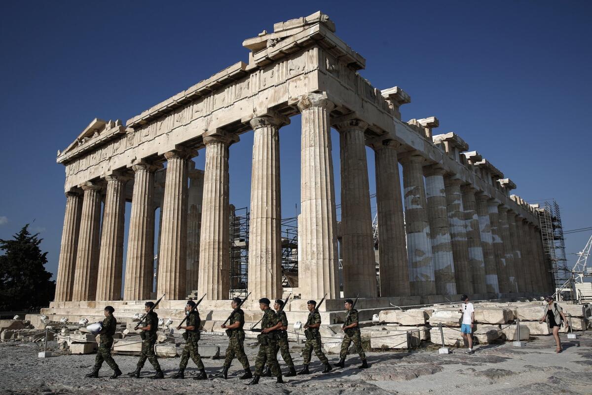 An army contingent carries a Greek flag in front of the Parthenon before a hoisting ceremony at the Acropolis Hill in Athens.