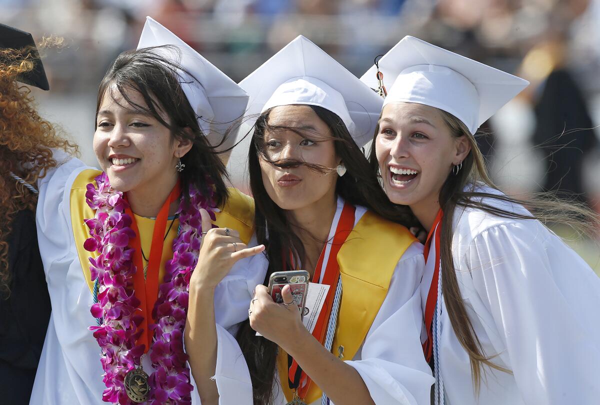 A happy group of graduates stops for a picture from parents as they walk into the Huntington Beach High graduation ceremony.