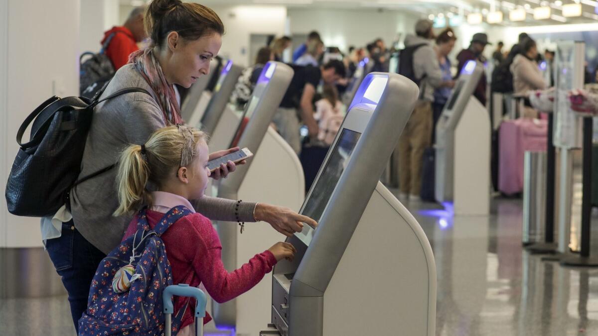 Katy Von Treskow, left, traveling with her 5-year-old daughter Madeline Von Treskow, uses self-check-in kiosk at Los Angeles International Airport on the day before Thanksgiving 2017.